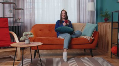 Evde genç bir kadın cep telefonu kullanıyor. Daktilo kullanıyor. 