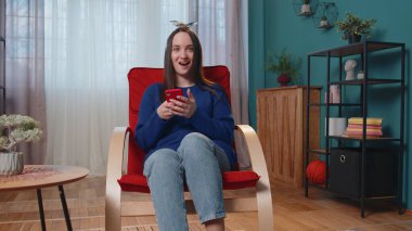 Evde genç bir kadın cep telefonu kullanıyor. Daktilo kullanıyor. 