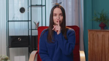 Genç bir kadın işaret parmağını dudaklarına bastırıyor. Sessizlik işareti yapıyor. Evde kimseye bir şey söyleme.