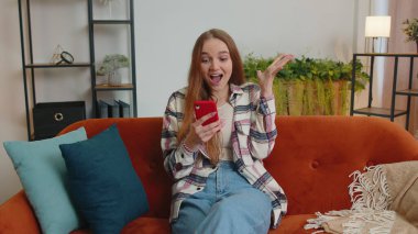 Evde genç bir kadın cep telefonu kullanıyor. Daktilo kullanıyor. 