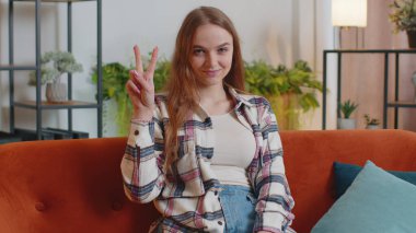 Kameraya bakan genç bir kadın zafer işareti gösteriyor, başarı umuduyla, kazanmak için, barış jesti yapıyor.