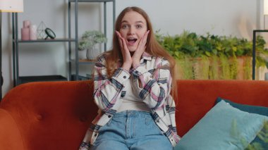 Kanepedeki ani zaferden dolayı şaşkınlıkla el kaldıran heyecanlı genç kadın.