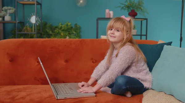 Niña de la escuela pequeña uso ordenador portátil aprendizaje lectura lecciones de educación en línea solo en casa —  Fotos de Stock