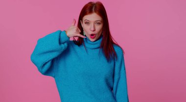 Mavi kazaklı neşeli kız kameraya bakıyor, telefon hareketleriyle beni geri ara diyor.