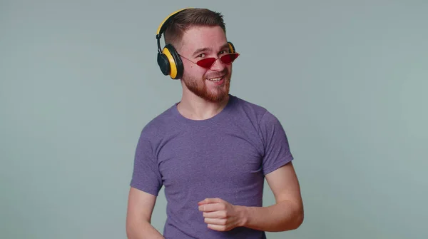 Alegre atraente homem ouvindo música via fones de ouvido e dançando disco brincando se divertindo — Fotografia de Stock