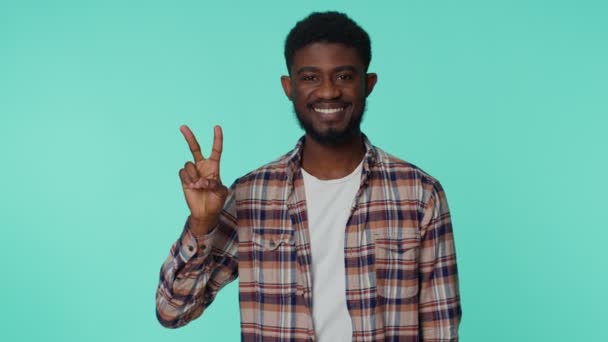 Hombre sonriente afroamericano mostrando signo de victoria, esperando el éxito y ganar, haciendo gesto de paz — Vídeo de stock