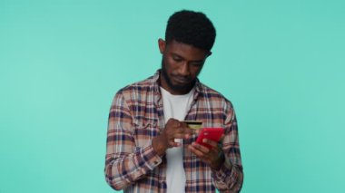 Genç adam banka kartı ve akıllı telefon kullanarak online alışveriş yapıyor.