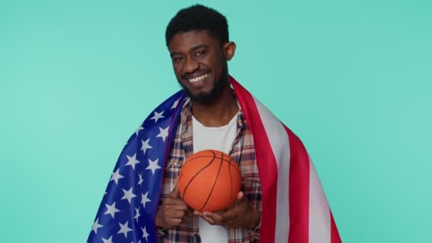 Barbudo joven fanático del baloncesto sosteniendo bandera estadounidense haciendo gesto ganador, bailando solo — Vídeo de stock