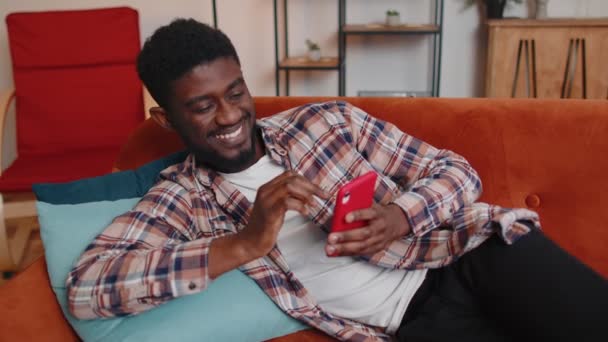Jonge volwassen man thuis gebruik maken van mobiele telefoon typen browsen zeggen wow ja ontdekte grote overwinning — Stockvideo