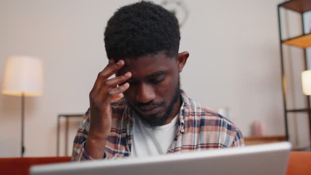 Afroamerykanin siedzi na kanapie otwierając laptop i rozpoczyna pracę online w salonie w domu — Wideo stockowe