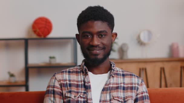 Portret van gelukkig Afrikaans amerikaanse tiener student guy glimlachen, kijken naar camera thuis op de bank — Stockvideo