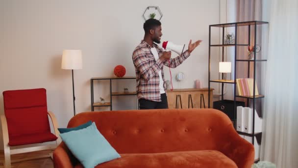 Junger Mann ruft in Megafon-Lautsprecher Rabatt-Verkauf von Immobilien zu Hause auf Sofa an — Stockvideo