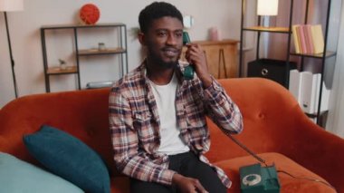 Yetişkin Afrikalı Amerikalı genç adam evdeki arkadaşlarıyla eski telefon konuşmalarından keyif alıyor.