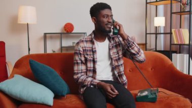 Yetişkin Afrikalı Amerikalı genç adam evdeki arkadaşlarıyla eski telefon konuşmalarından keyif alıyor.