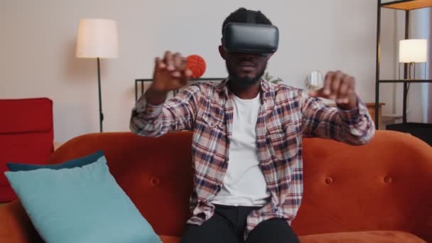 Молодой человек использует очки для гарнитуры виртуальной реальности дома, наслаждаясь видео концепцией движения руками в воздухе — стоковое видео