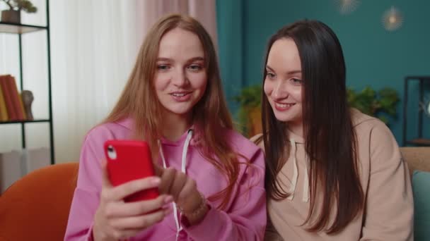 Twee vrouwelijke vrouw vrienden familie kijken naar grappige films op de smartphone, online comedy film thuis — Stockvideo