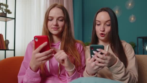 Flickor vänner syskon fira framgång vinna skrika jubel, gör online shopping på smartphone — Stockvideo