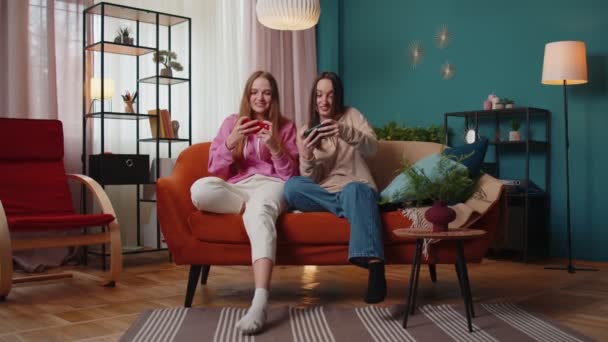 Zwei lustige Freundinnen spielen begeistert Rennvideospiele auf dem Smartphone — Stockvideo