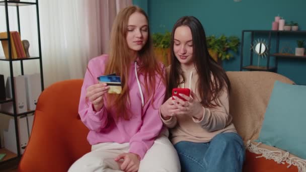 Cheerful girls friends using credit bank card and smartphone while transferring money, purchases — Stock Video