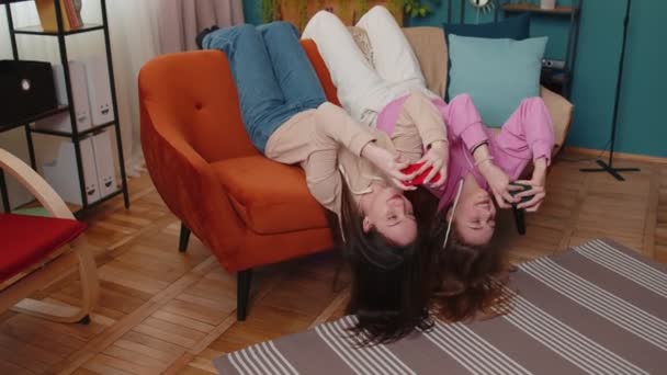 Ανησυχούσε δύο αστεία κορίτσια φίλους αδέλφια με ενθουσιασμό παίζει αγωνιστικά βιντεοπαιχνίδια στο smartphone — Αρχείο Βίντεο