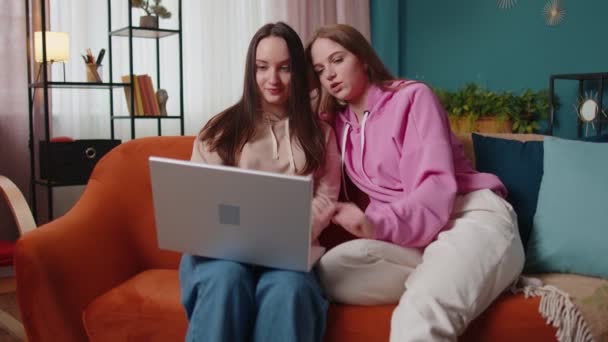 Щасливі дві жінки пара сім'ї на дивані вдома, насолоджуватися балачками, проводити дозвілля на ноутбуці — стокове відео
