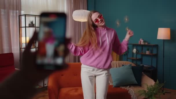 Joyful blogger adolescente chica bailando en la cámara filmando vídeo utilizando el teléfono móvil en casa en la sala de estar — Vídeos de Stock