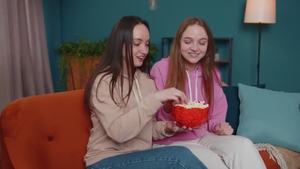 Izgalmas lányok barátok testvérek szórakozás néz kedvenc tv sport mérkőzés, eszik popcorn, otthon kanapé — Stock videók