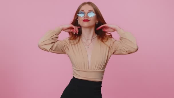 Menina morena alegre sedutora em blusa bege usando óculos de sol, sorriso encantador na parede rosa — Vídeo de Stock
