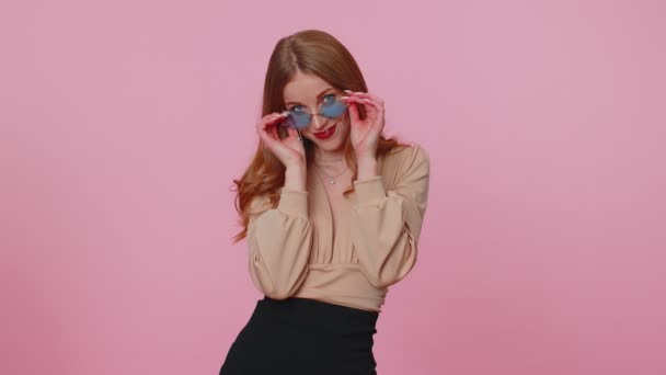 Sincere cool cheerful brunette girl in beige blouse wearing sunglasses, charming smile on pink wall — Stock Video