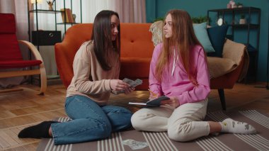 Tatmin olmuş kız arkadaşlar arkadaşlar aile bütçesini dolar olarak hesaplarlar. Evde bir deftere yazarlar.