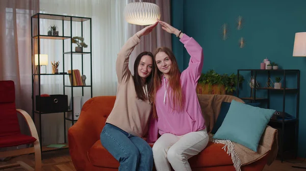 Chicas felices hermanos haciendo señal de gesto de techo de manos, nueva casa, propiedad, seguro, préstamo bancario — Foto de Stock