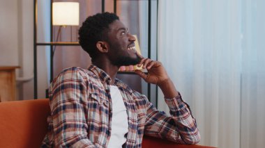 Mutlu, sakin, Afro-Amerikan sakallı, gülümseyen, başka tarafa bakan, dinlenen, tatmin olmuş genç adam.