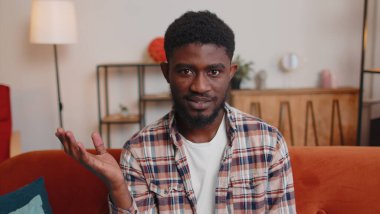 Adam evde kanepede oturuyor, kameraya bakıyor, arkadaşlarıyla veya aileleriyle görüntülü görüşme yapıyor.