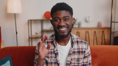 Adam evde kanepede oturuyor, kameraya bakıyor, arkadaşlarıyla veya aileleriyle görüntülü görüşme yapıyor.