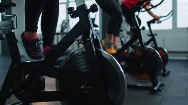 Bir grup gülümseyen arkadaş. Modern spor salonunda kadın sınıfı spor yapıyor, antrenman yapıyor, bisiklete biniyor.