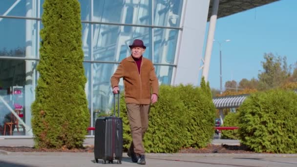 Старший пенсионер туристический дедушка бизнесмен, идущий от ворот аэропорта с багажной сумкой — стоковое видео