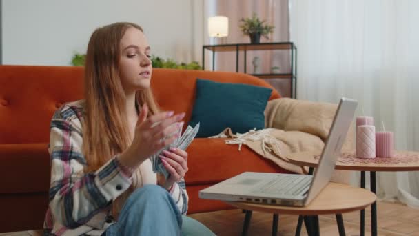 Sorrindo feliz jovem contando dinheiro em dinheiro e usar laptop pc calcular contas domésticas em casa — Vídeo de Stock