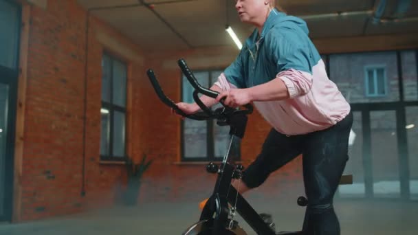 Vrouw voert aeroob uithoudingsvermogen training workout cardio routine op de simulatoren, cyclus training — Stockvideo