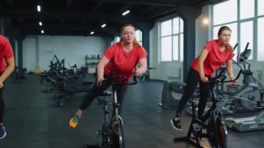 Grup atletik kızlar spor salonunda bisiklet sürme egzersizleri yapıyorlar.