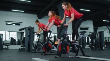 Spor salonunda bisiklet çevirme antrenmanına katılan atletik kadın grubu, içeride kilo kaybı.