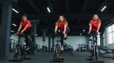 Bir grup kız, bisiklet simülatörlerinde aerobik antrenmanı yapıyor.