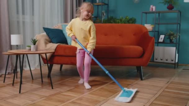 Enfant fille enfant lave les planchers avec une serpillière dans le salon domestique danse, chantant d'humeur positive — Video