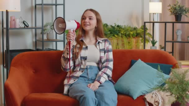 Tânăra femeie strigă în difuzor megafon anunță reduceri de vânzare de bunuri imobiliare acasă pe canapea — Videoclip de stoc
