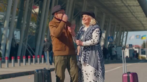 Idős férj feleség nyugdíjasok turisták megy a repülőtér terminál beszállás poggyász kerekeken — Stock videók