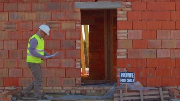 Architecte ouvrier constructeur professionnel analyse les plans, les dimensions sur le chantier de la maison de construction — Video