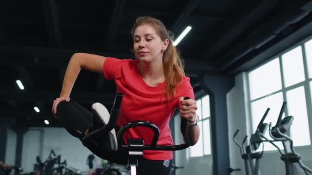 Sportowe kobiety szkolenia grupowe rozciągające się na spinning stacjonarne rutynowych rowerów w siłowni, w pomieszczeniach — Wideo stockowe