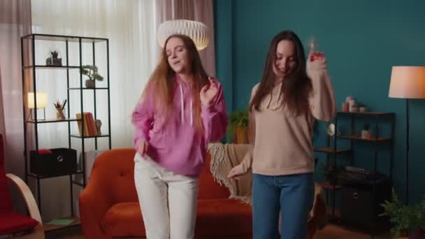 Ευτυχισμένα δύο έφηβα κορίτσια αδέλφια ή bloggers ζευγάρι χορεύουν στο σπίτι διασκεδάζοντας απολαμβάνοντας μοντέρνο χορό — Αρχείο Βίντεο