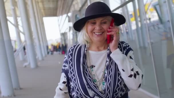 Grande-mère touristique senior marche, salle de l'aéroport international en utilisant la conversation de téléphone mobile — Video