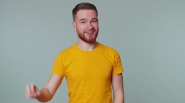 Yakışıklı gülümseyen adam zafer işareti gösteriyor, başarı ve kazanmayı umuyor, barış jesti yapıyor.