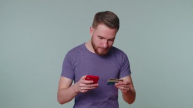 Kredi kartı ve akıllı telefon kullanan bir turist online alışverişleri aktarırken,